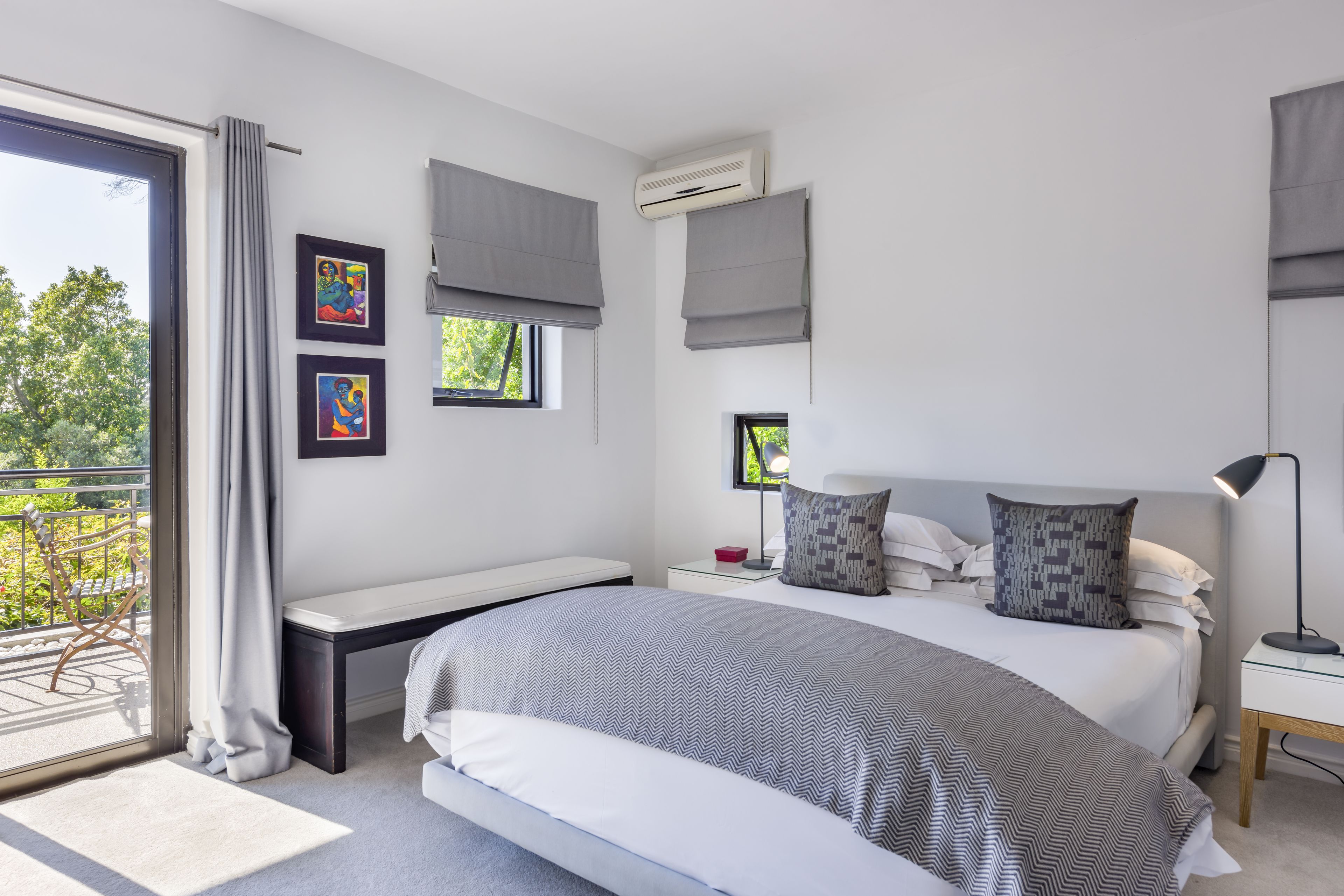 Quarto moderno com uma cama grande, uma mesa de cabeceira, cortinas e uma varanda.