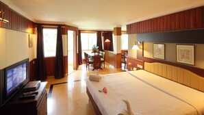 Ein Hotelzimmer mit Bett, Schreibtisch, Fernseher und Fenster.