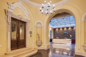 A grand lobby with ornate woodwork, a chandelier, a reception desk, and a skylight. - Eurostars Palazzo Zichy (Budapest)