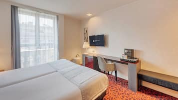 Una habitación de hotel con una cama grande, un escritorio con silla, televisión y cafetera.