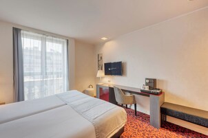Una habitación de hotel con una cama grande, un escritorio con silla, televisión y cafetera.