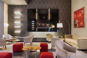 En moderne lobby med siddeområder, et stort kunstværk på væggen og en moderne lampe.