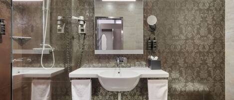 A modern bathroom with a glass-enclosed shower, a white sink, and a large mirror above the sink.