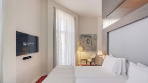 Une chambre d’hôtel avec un lit, une télévision, une chaise et une lampe.