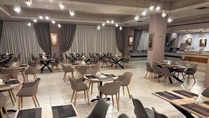 A modern dining area with multiple tables and chairs, overhead lighting, and curtains. - Achillio Hotel (Komotini)