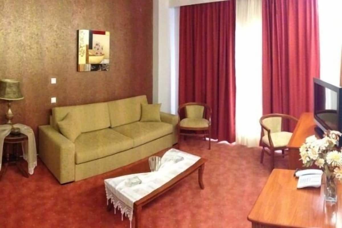 Una sala de estar con un sofá, una mesita, una lámpara y un televisor.
