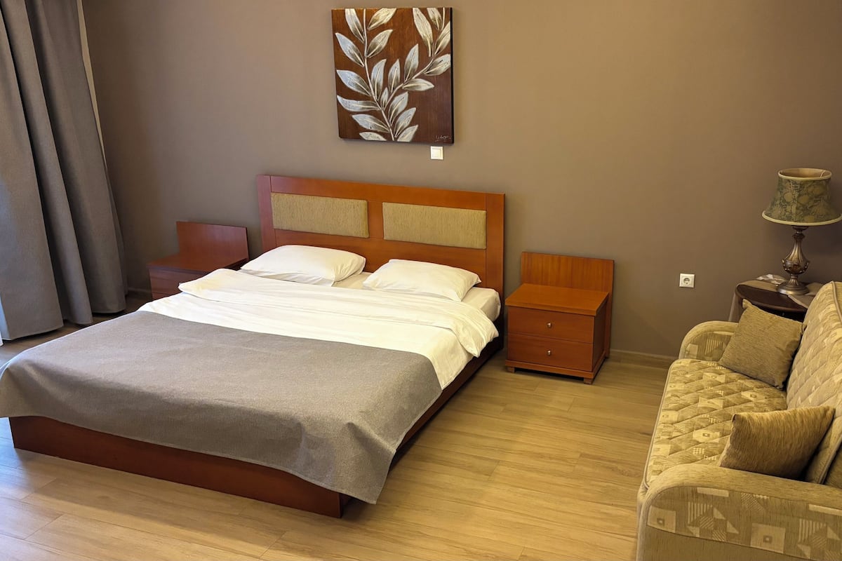 Un dormitorio con cama, mesita de noche y sofá.