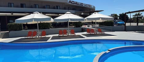 Una piscina al aire libre de temporada, sombrillas