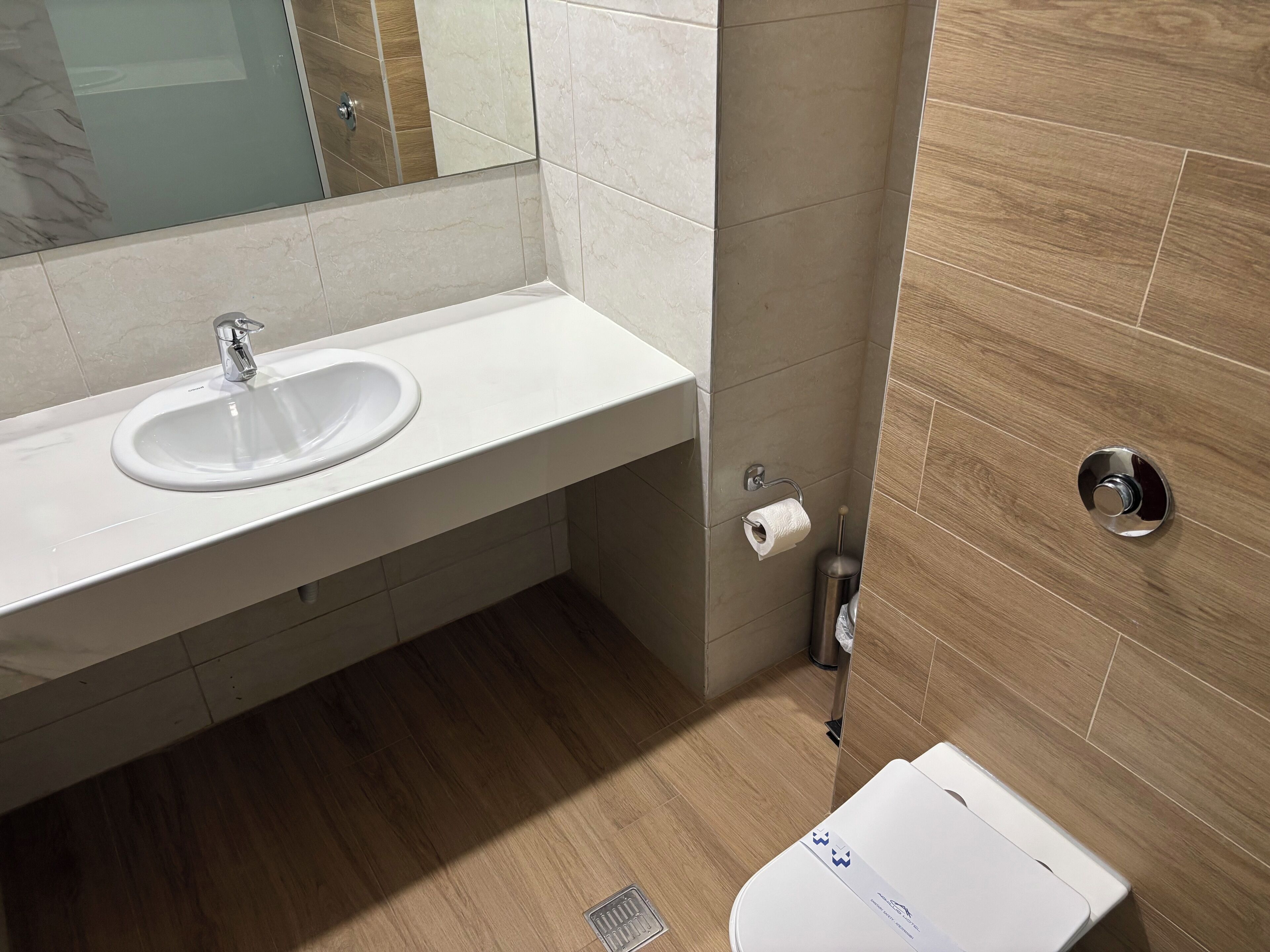 A modern bathroom with a white sink, mirror, and toilet.