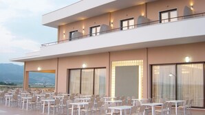 A modern hotel with a flat roof, large windows, and outdoor seating. - Achillio Hotel (Komotini)