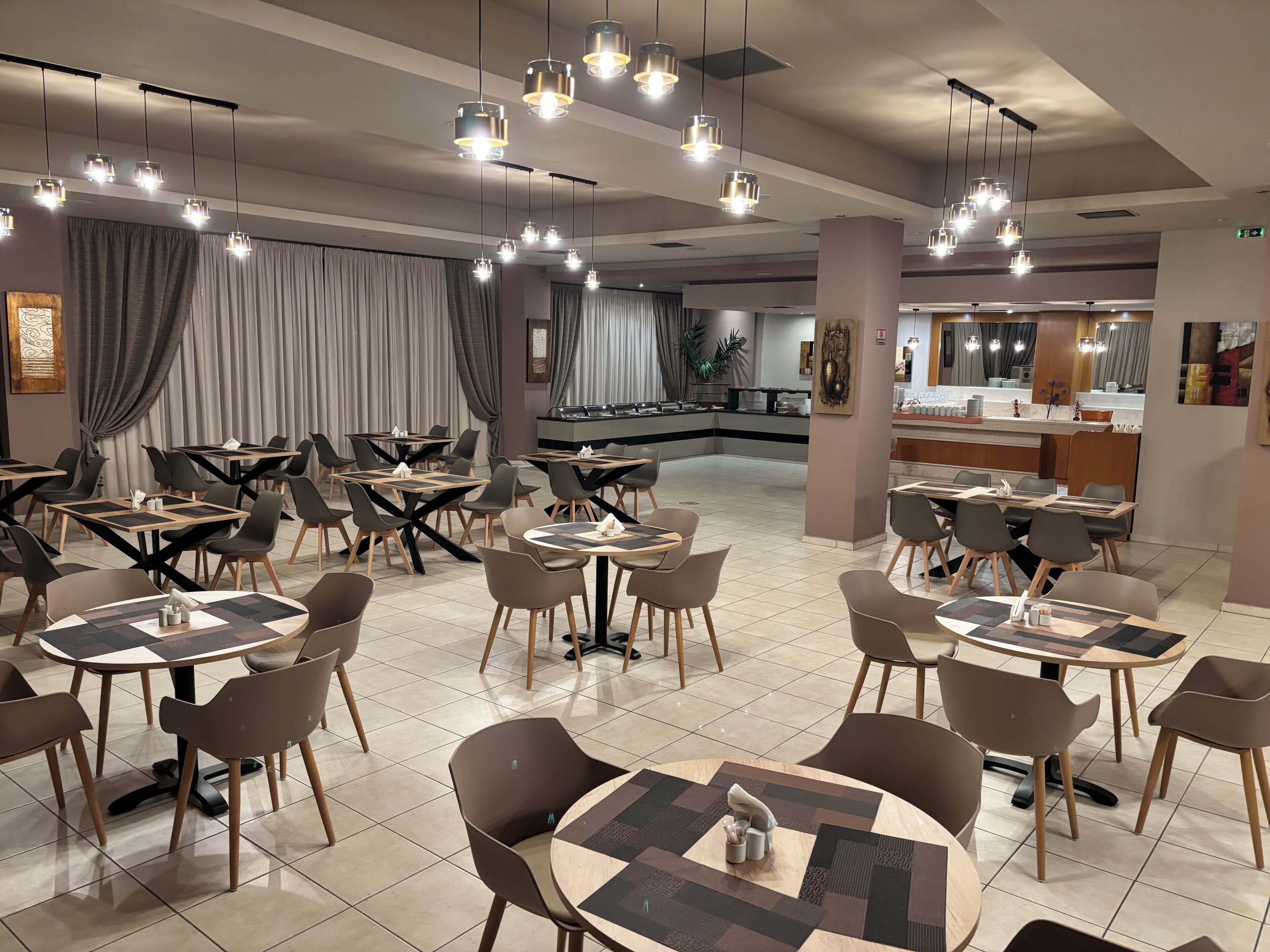 Un restaurant moderne avec des tables rondes, des chaises et des luminaires suspendus.
