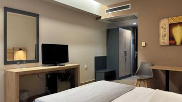 Een hotelkamer met een bed, een bureau met een televisie, een stoel, een kledingkast en een schilderij aan de muur.