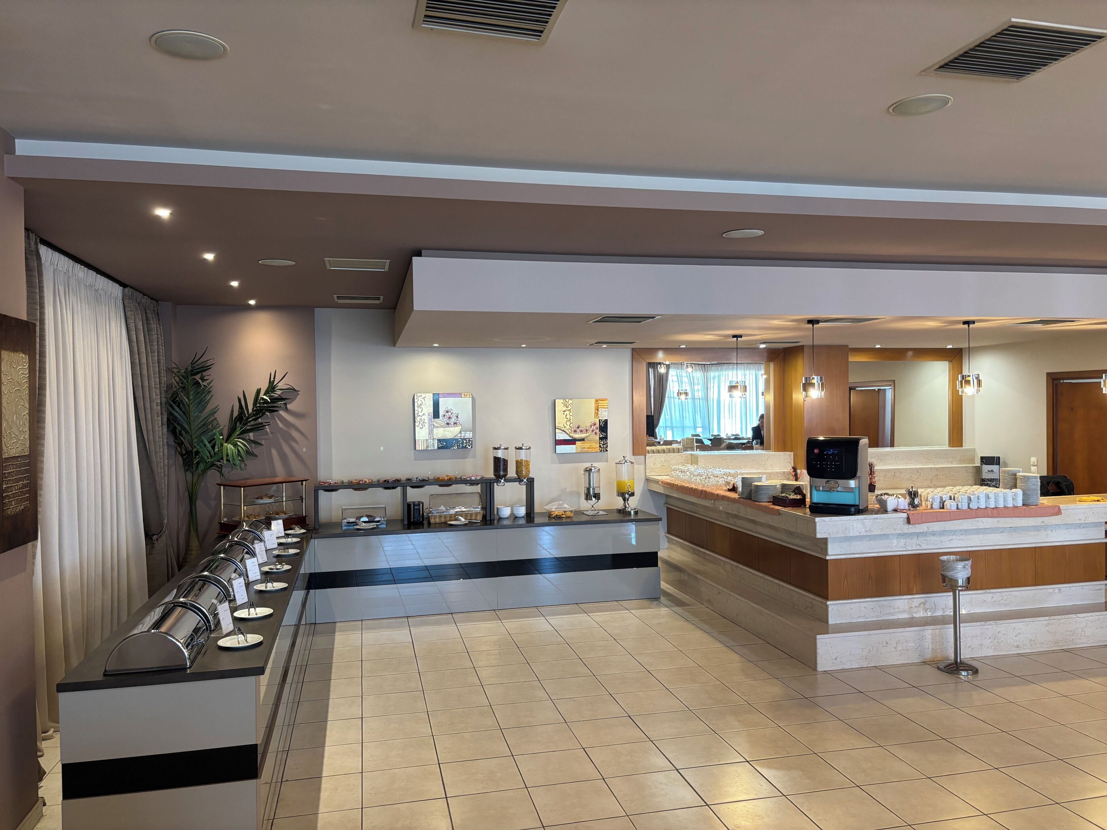 Un hall d’hôtel comprenant un espace buffet, un comptoir d’accueil et un grand miroir.