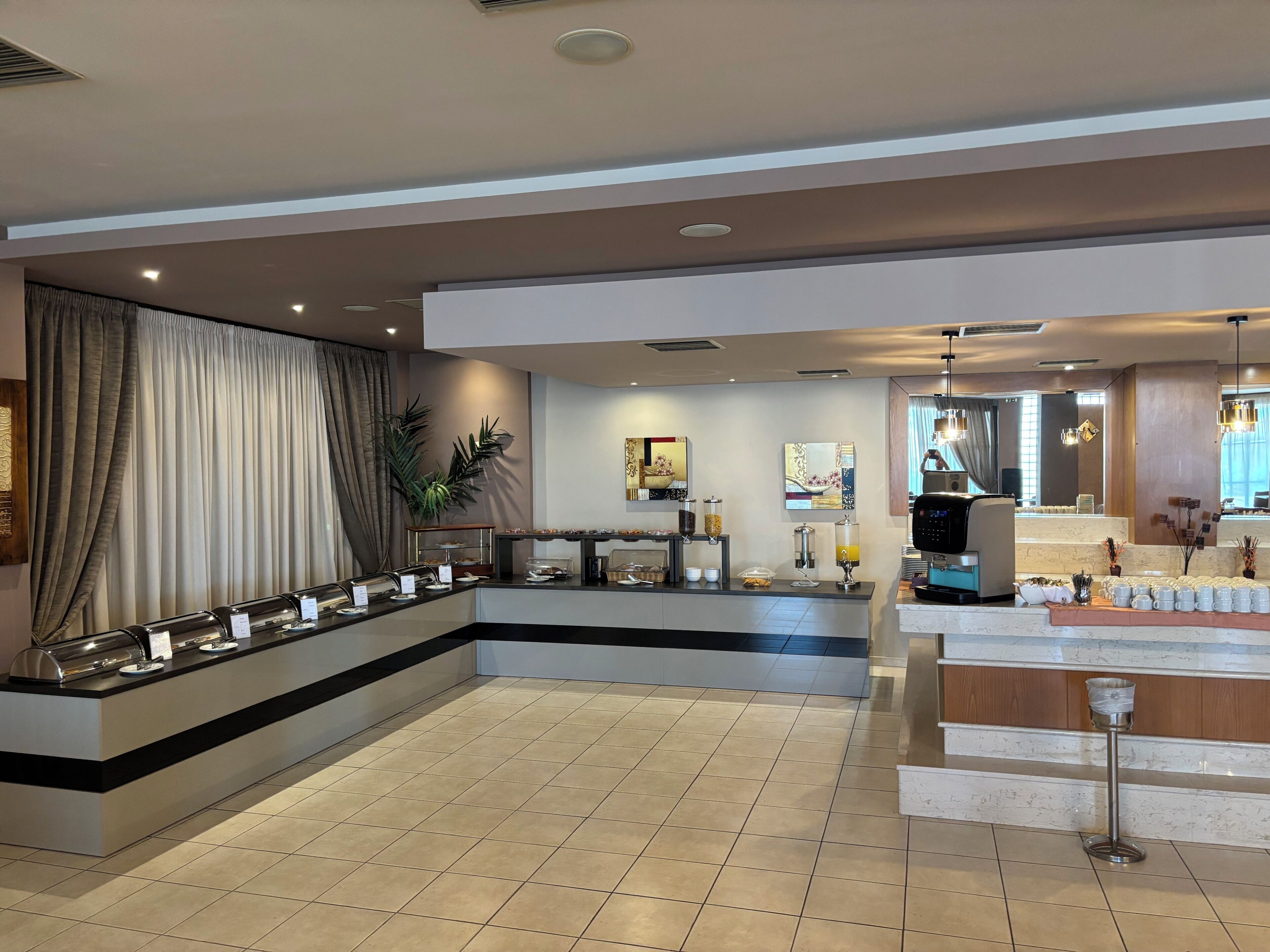 Un vestíbulo de hotel con zona de buffet, estación de café y área de descanso con vistas.