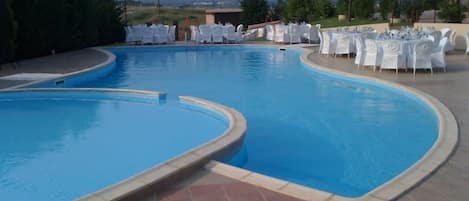 Una piscina al aire libre, sombrillas, sillones reclinables de piscina