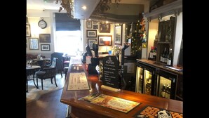 Zona de bar con mostrador de madera, carteles con la carta y un árbol de Navidad.