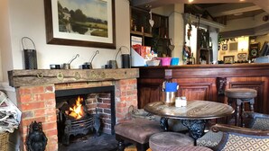 Una habitación acogedora con chimenea, una mesa redonda de madera y una zona de bar.
