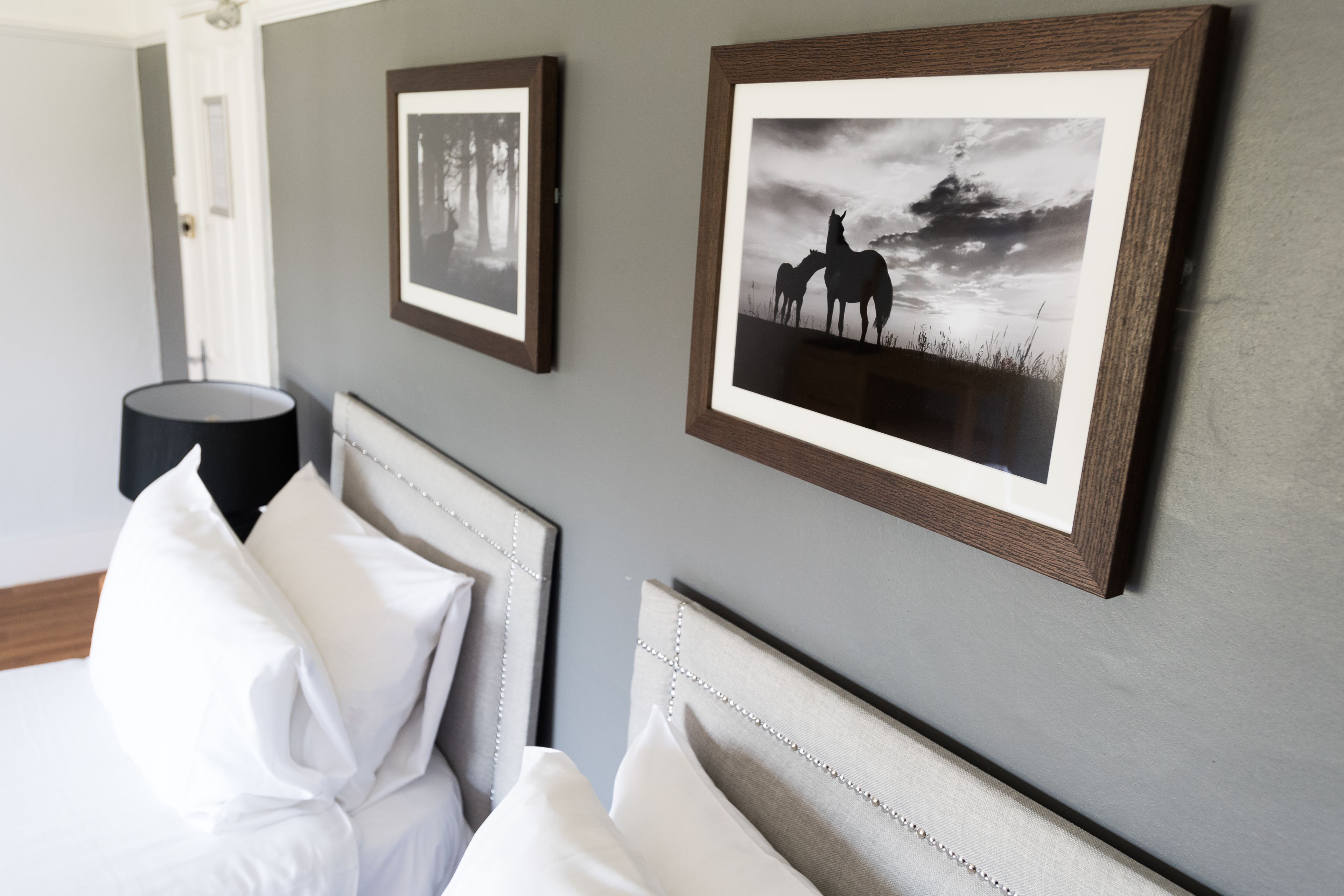 A neatly arranged bedroom with a bed, pillows, and framed pictures on the wall.