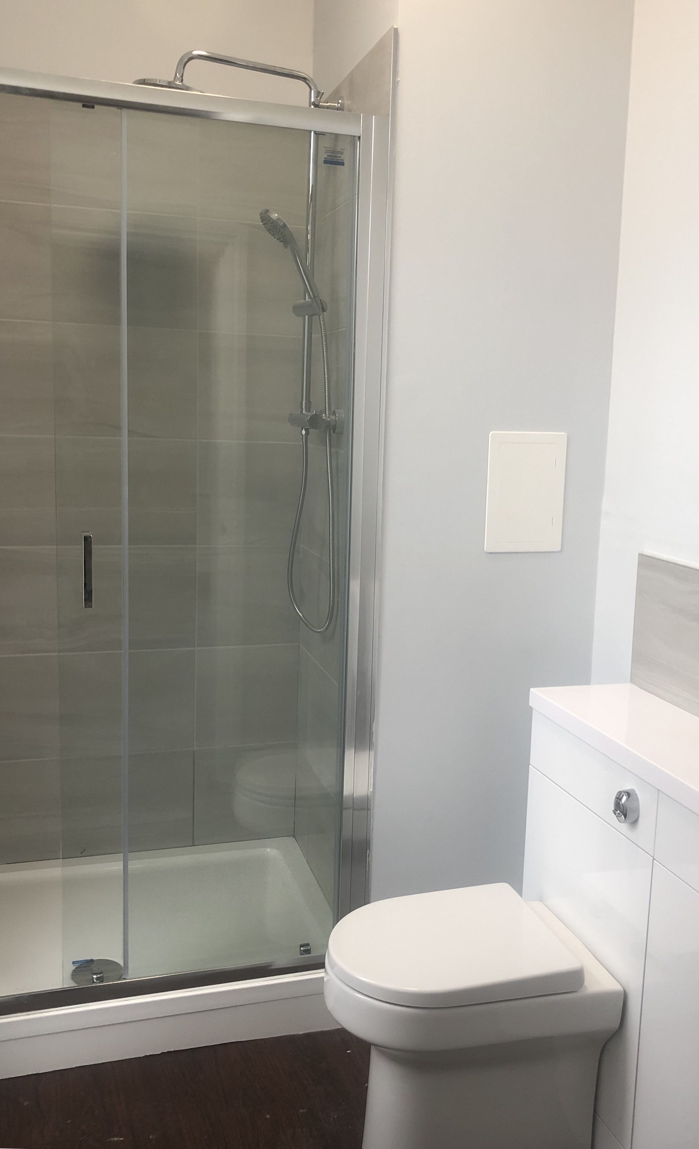 A bathroom with a glass-enclosed shower, a white toilet, and a white sink.