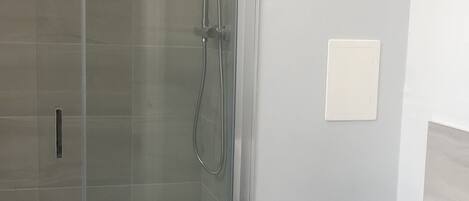 A bathroom with a glass-enclosed shower, a white toilet, and a white sink.