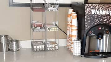 A coffee station with a coffee machine, cups, and a coffee bean display.