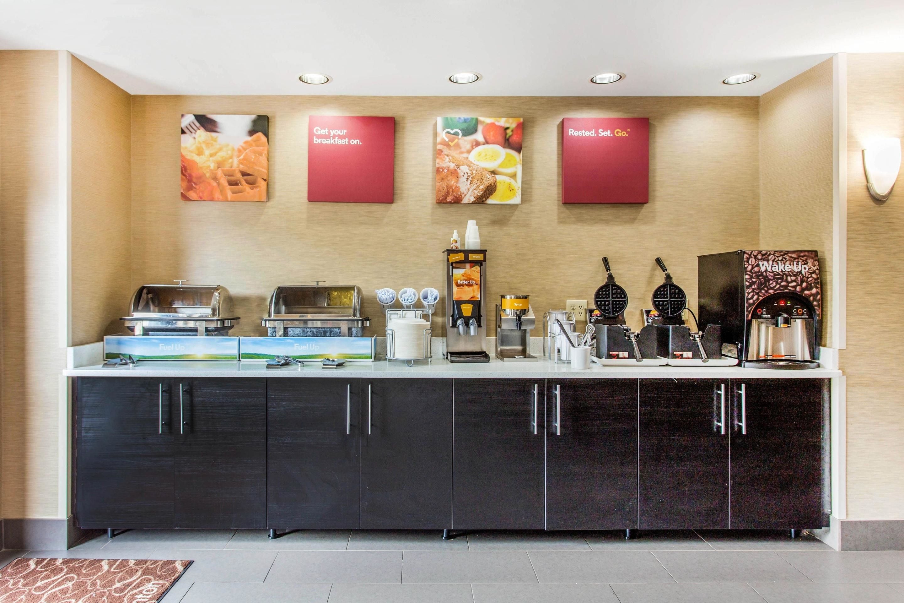 A breakfast bar with waffle makers, coffee machines, and a variety of food options.
