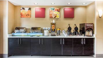 A breakfast bar with waffle makers, coffee machines, and a variety of food options.