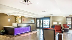 Zona de recepción de hotel con un mostrador moderno, área de estar y amplios ventanales.