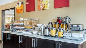 Un bufé de desayuno con diversos alimentos, máquinas de café y un tostador.