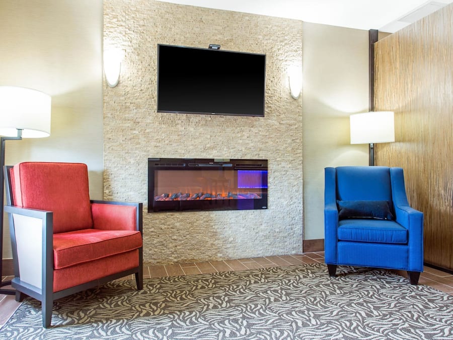 Een hotel lobby met een open haard, twee fauteuils en een flatscreen televisie aan de muur.
