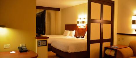 Une chambre d’hôtel avec deux lits, un bureau, une chaise et une petite table.