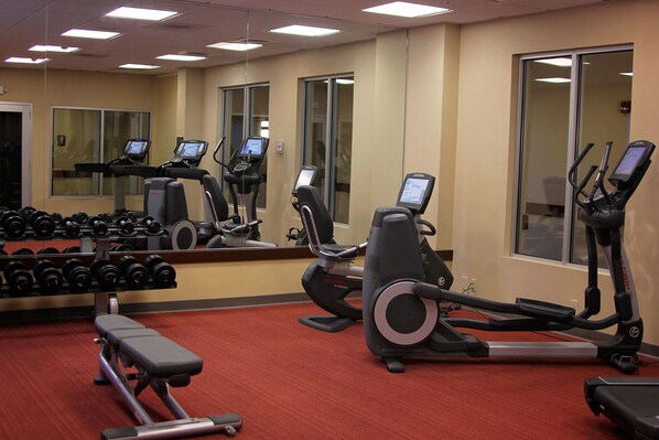 A gym with treadmills, elliptical machines, and a bench.