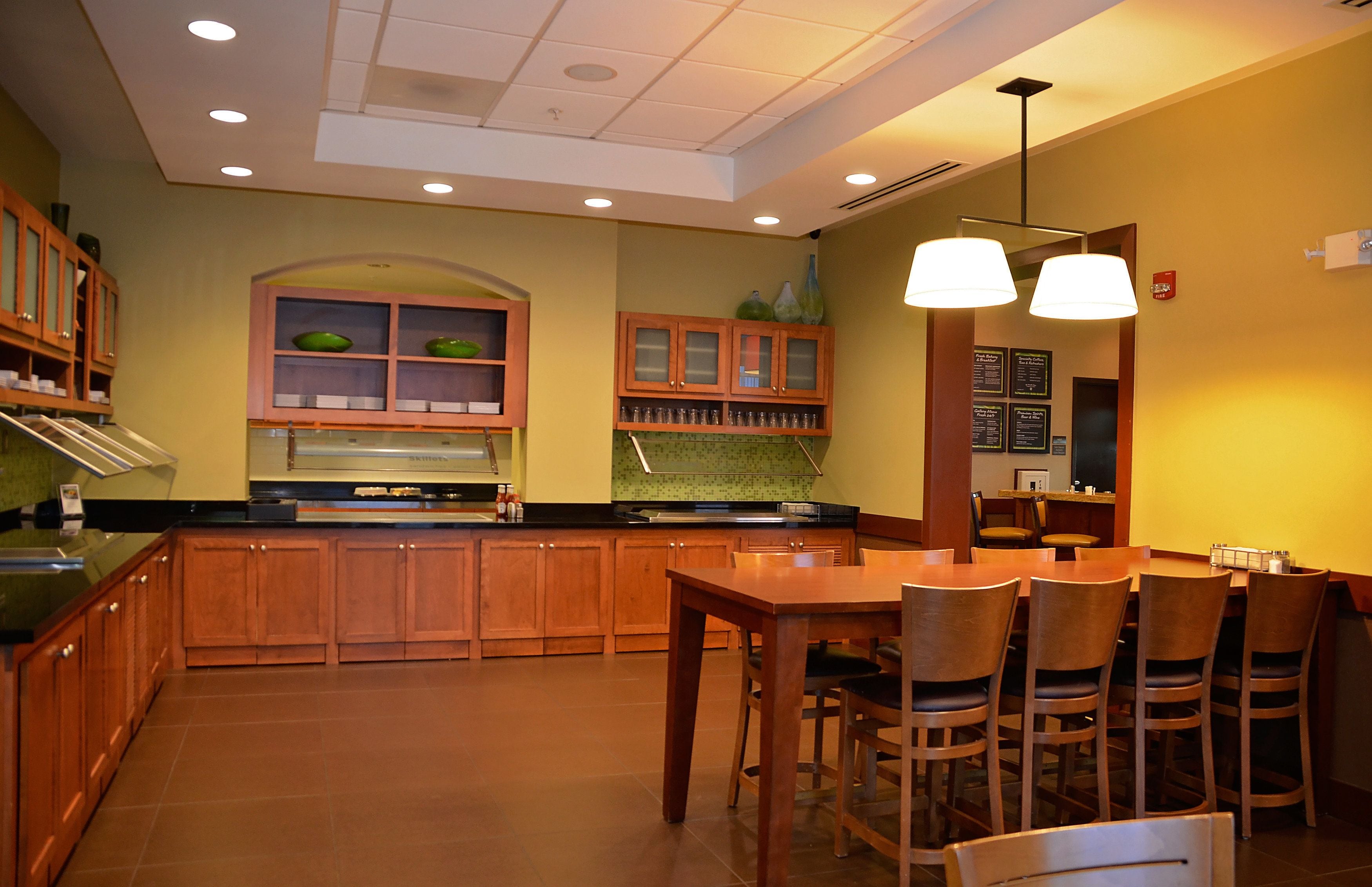 A kitchen with wooden cabinets, a dining table with chairs, and pendant lights.