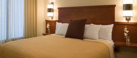 A hotel room with a large bed, two bedside tables with lamps, and a window with curtains.