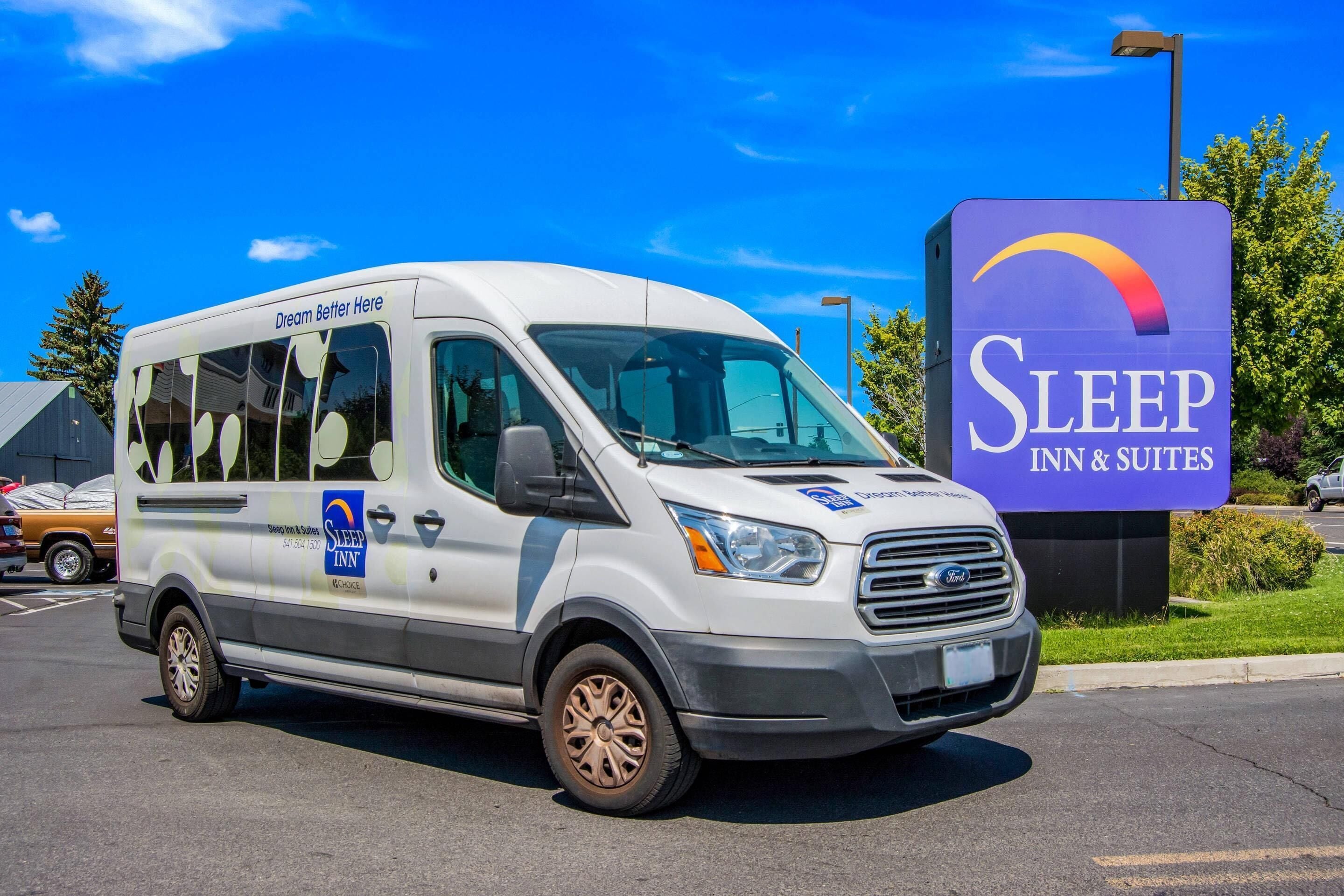A white van with 'Sleep Inn & Suites' branding parked in front of a sign.
