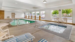 A hotel lobby with a pool area, including a hot tub, lounge chairs, and a view of the outside.