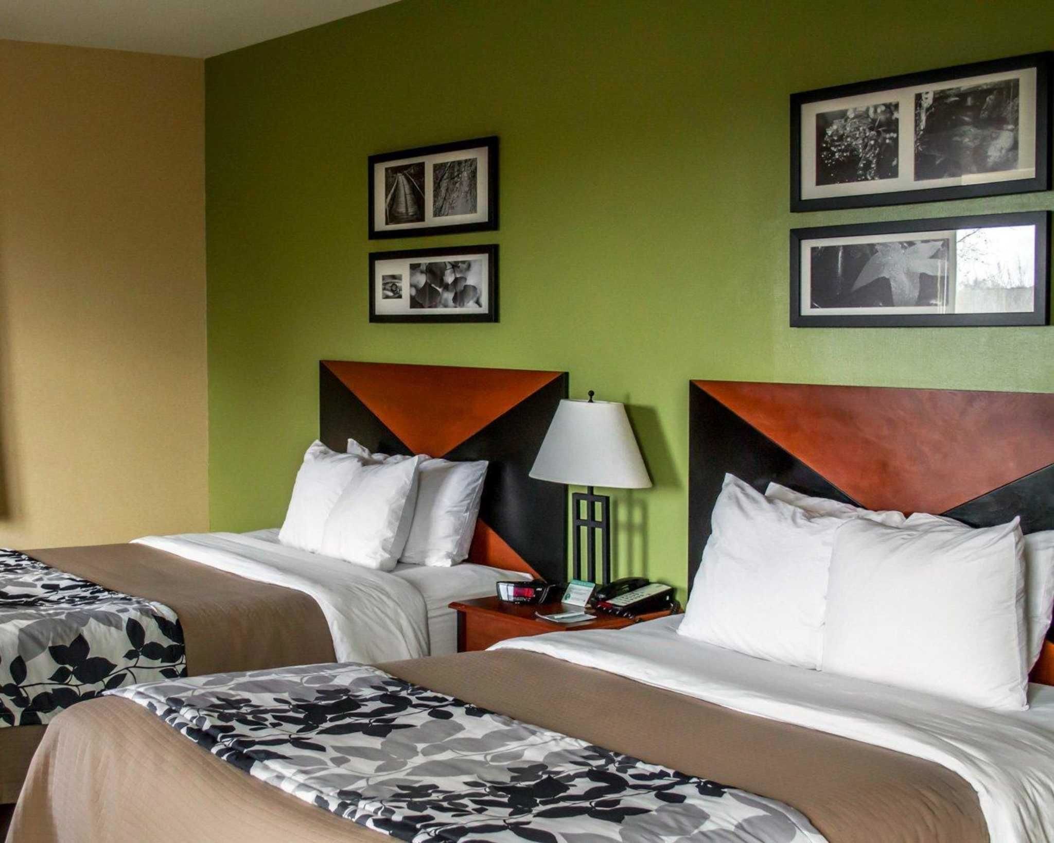 A hotel room with two beds, green walls, and framed pictures on the wall.