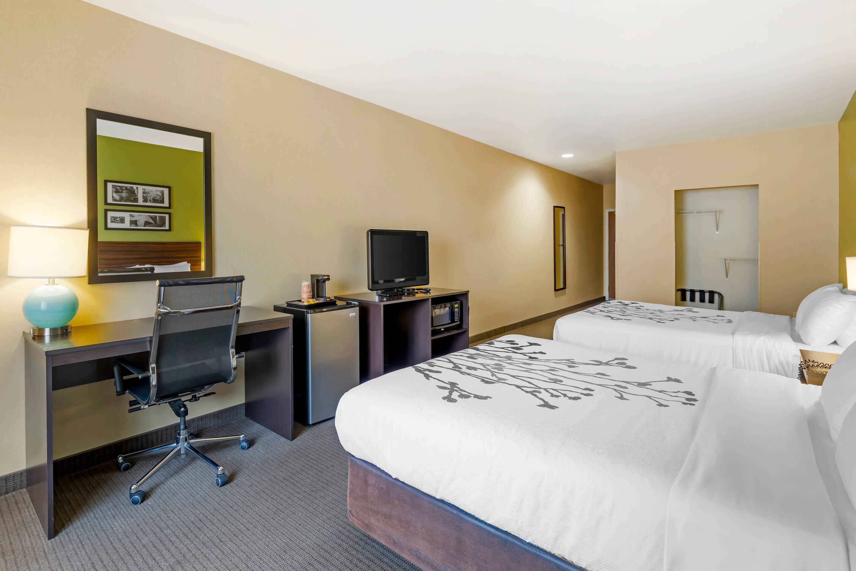 Una habitación de hotel con escritorio, silla, televisor y dos camas.