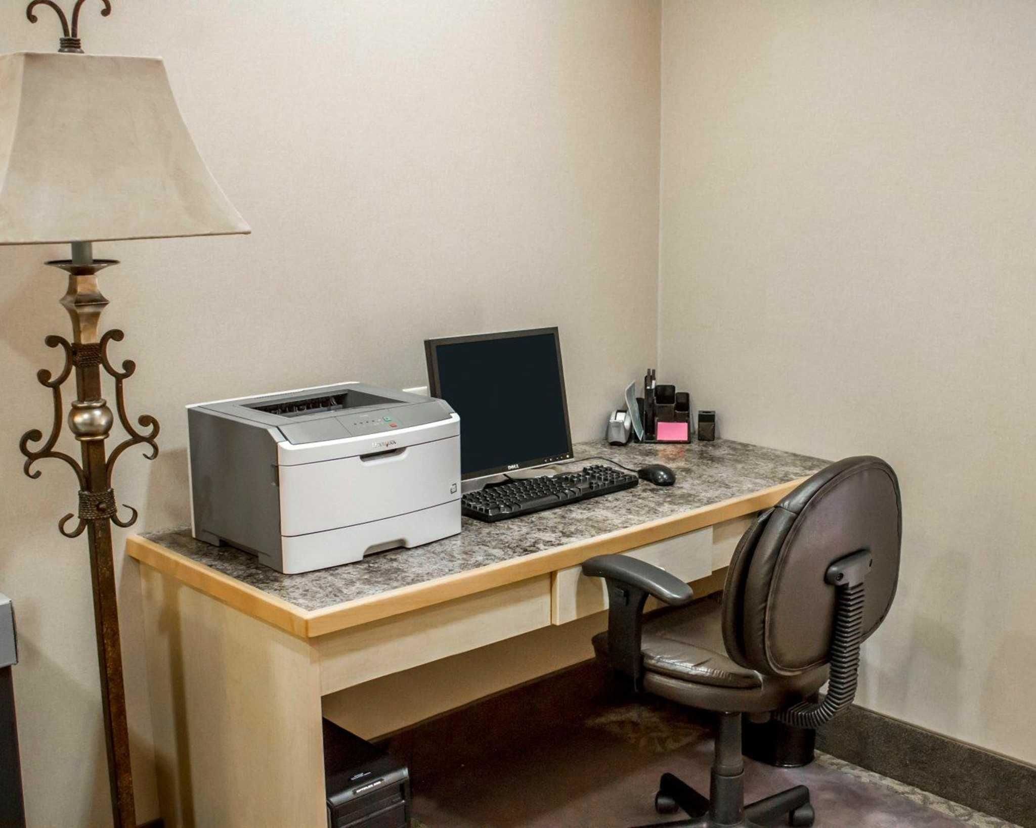 A home office setup with a desktop computer, printer, and a lamp.