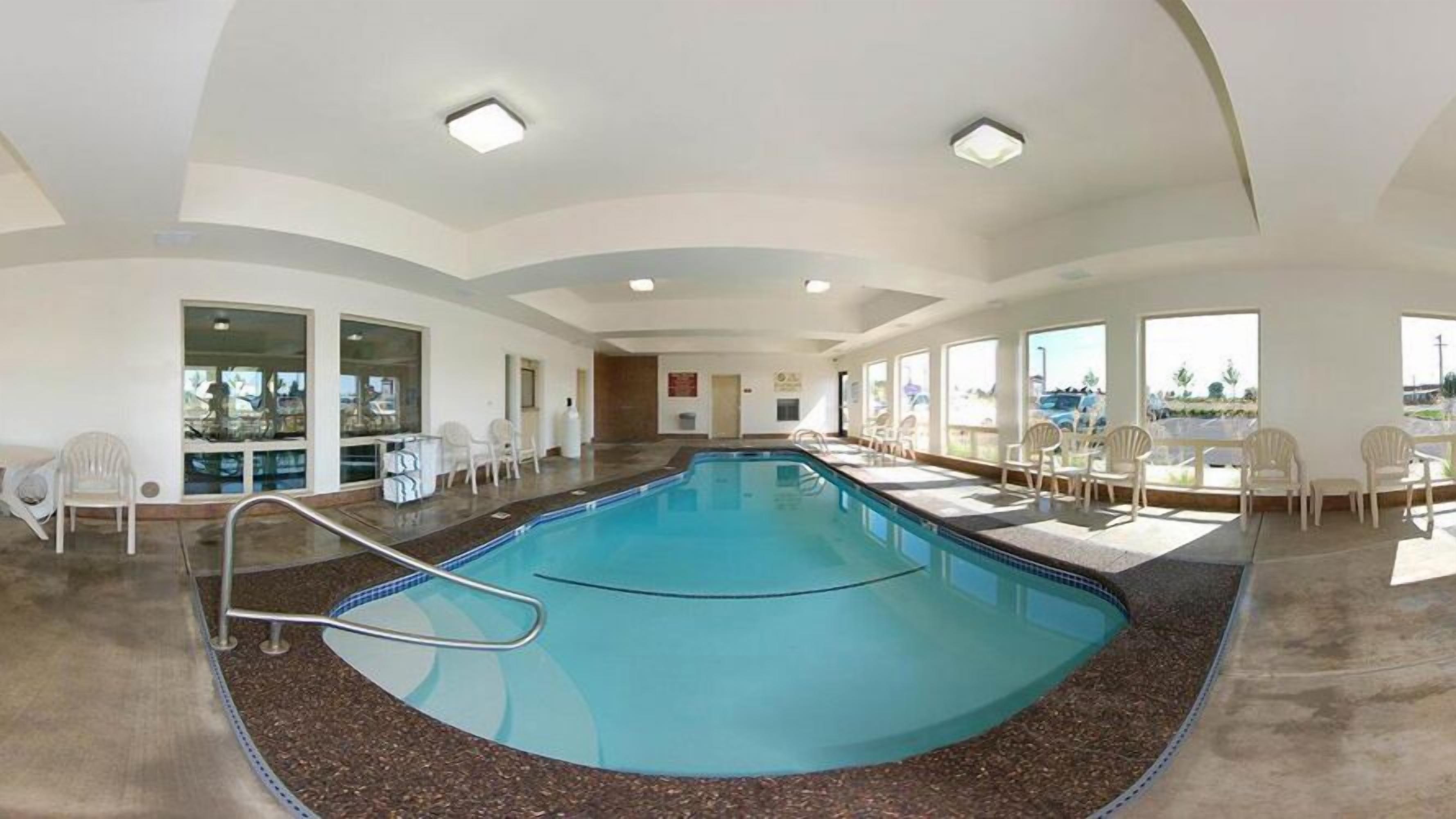 Una amplia piscina cubierta con vistas despejadas del entorno, incluyendo un área de descanso con sillas y vistas al exterior.