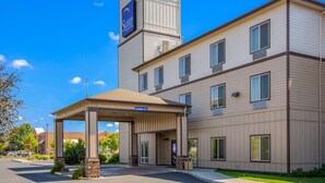 A hotel with a covered entrance, a sign for 'Sleep Inn & Suites', and a clear blue sky.