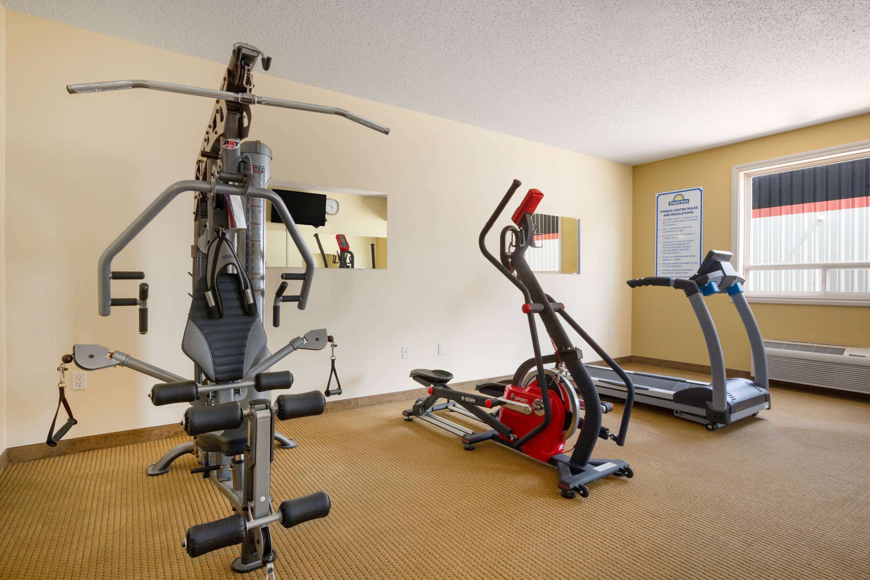 A gym with exercise equipment including a multi-functional machine, a stationary bike, and treadmills.