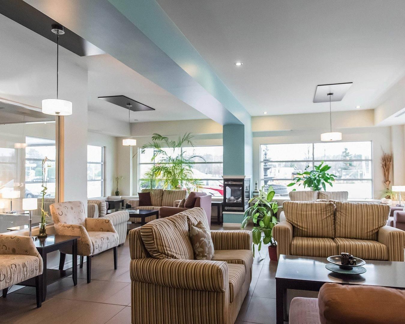 A spacious hotel lobby with multiple seating areas, large windows, and indoor plants.