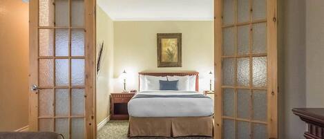 A hotel room with a bed, a nightstand, a lamp, and a painting on the wall.