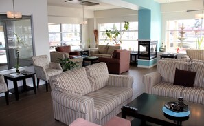 A spacious living room with striped sofas, a coffee table, and a fireplace. - Quality Inn Mont-Laurier (Mont-Laurier)