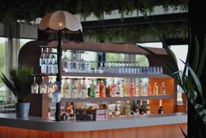Una zona de bar con estantes llenos de botellas y una lámpara colgante.