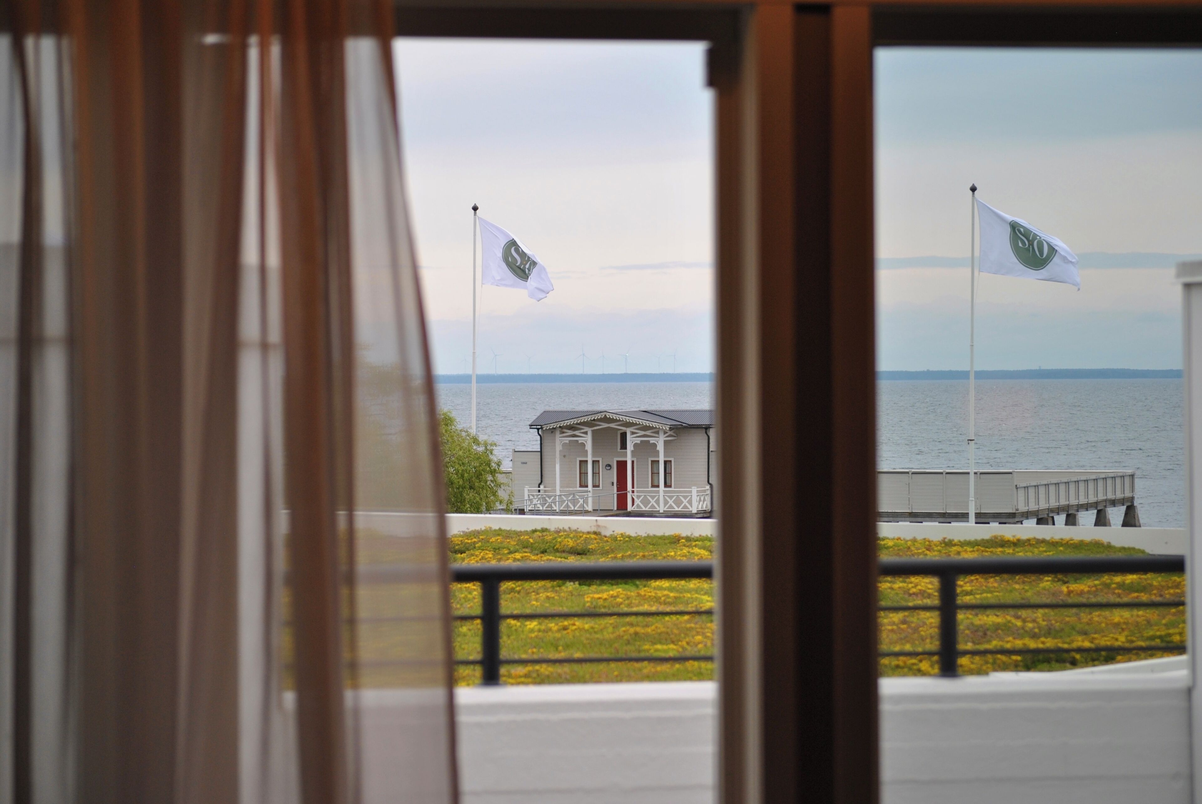 Ein Blick durch ein Fenster mit einem Gebäude und einem Steg im Hintergrund.