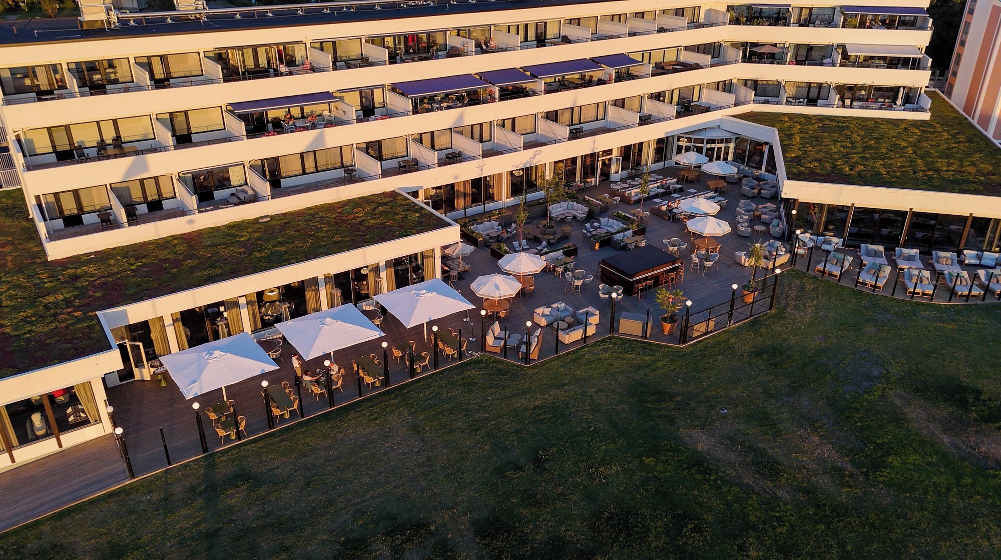 Et hotel med flere etager, udendørs siddepladser og en tagterrasse.