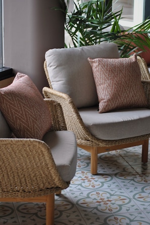 A wicker chair with a grey cushion and a patterned pillow. - Strand Öland (Borgholm)