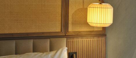 A bed with a headboard, a wall-mounted lamp, and a textured wall.